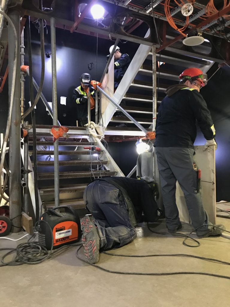 Construction workers installing modular staircase in offshore interior